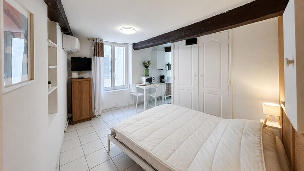 Ein Schlafzimmer mit Bett, Schreibtisch, Stuhl, Fernseher und Fenster.