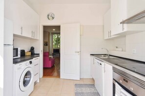 A compact kitchen with a washing machine, a microwave, and a sink. - Lightoasis Oeiras 2 (Oeiras)
