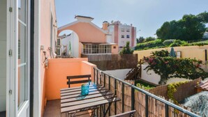 A balcony with a table and chairs, a view of neighboring buildings, and a wooden fence. - Lightoasis Oeiras 2 (Oeiras)