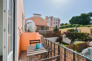 A balcony with a table and chairs, a view of neighboring buildings, and a wooden fence. - Lightoasis Oeiras 2 (Oeiras)