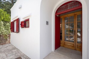 Ein Gebäude mit weißer Fassade, roten Fensterrahmen und einer Holztür mit Glasscheiben.