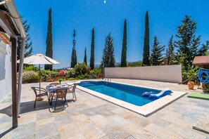 Ein rechteckiger Swimmingpool mit blauer Innenseite, umgeben von Steinfliesen.