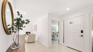 Un pasillo con un banco de madera, un espejo grande y una puerta que da a otra habitación.