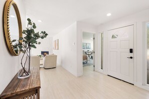 A hallway with a wooden bench, a large mirror, and a door leading to another room. - New Luxury House Near Golf, Trails & Restaurants. Voted "Top 10 Best New Houses" (La Quinta)