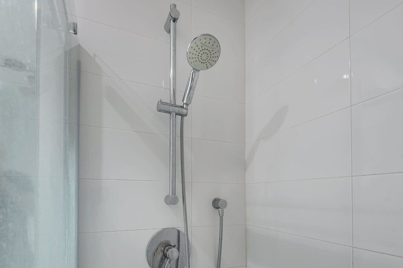 Eine Dusche mit Duschkopf, Handbrause und Duschschlauch.