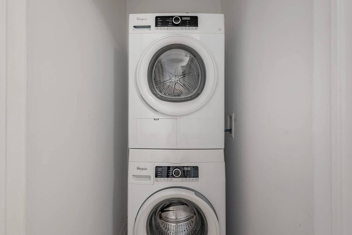Une machine à laver et un sèche-linge superposés dans une pièce aux murs sobres.