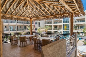 A covered outdoor seating area with wicker furniture and a thatched roof. - 2BR Condo w/ Pool & Jacuzzi, near Eagle Beach (Eagle)