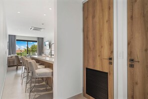 A modern kitchen with a wooden door, bar stools, and a view of the outdoors. - 2BR Condo w/ Pool & Jacuzzi, near Eagle Beach (Eagle)