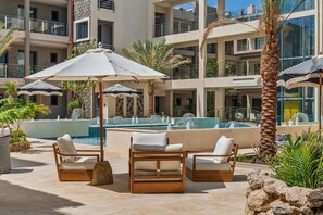 A poolside area with lounge chairs, umbrellas, and a water feature. - 2BR Condo w/ Pool & Jacuzzi, near Eagle Beach (Eagle)