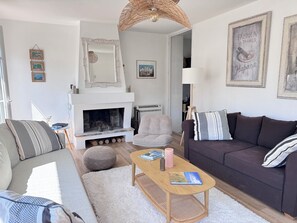 Ein Wohnzimmer mit Kamin, Sofa, Couchtisch und Sessel.