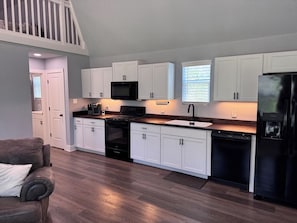 A modern kitchen with white cabinets, a black refrigerator, and a built-in oven.