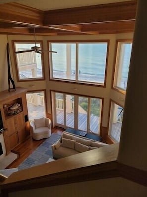 A high-ceiling room with large windows, a staircase, a fireplace, and a seating area. - Plantation at St George Island Fl. Beautiful beach view from all bedrooms (East Point)