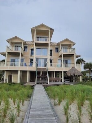 A multi-story beachfront hotel with a central staircase, balconies, and a thatched structure. - Plantation at St George Island Fl. Beautiful beach view from all bedrooms (East Point)