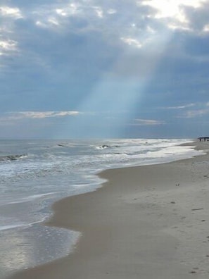 A beach with a curved shoreline, a pier, and a cloudy sky. - Plantation at St George Island Fl. Beautiful beach view from all bedrooms (East Point)