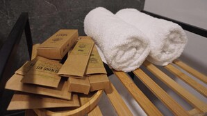 Eine hölzerne Bank mit zwei aufgerollten weißen Handtüchern und mehreren Kartons mit der Aufschrift 'SEMINING KIT' an einer Marmorwand.