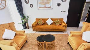 Ein Wohnzimmer mit Sofa, zwei Sesseln, einem Couchtisch und Dekorationselementen.