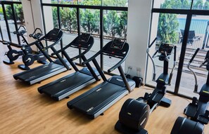 A row of treadmills in a gym with a view of trees outside. - Modern 2Bed Exclusive Apartment at Signature Accra (Accra)