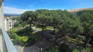 A residential area with a curved driveway, trees, and a clear blue sky. - Bright apartment with balcony and swimming pool (Fréjus)