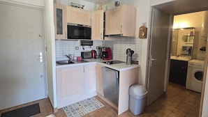 A compact kitchen with a microwave, toaster, sink, and a small trash bin. - Bright apartment with balcony and swimming pool (Fréjus)