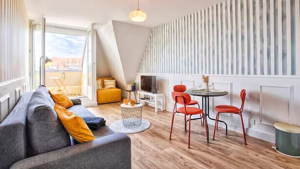 A modern living room with a sofa, a dining table with chairs, and a view of the outdoors. - Studio with balcony in Villers-sur-Mer (Villers-sur-Mer)