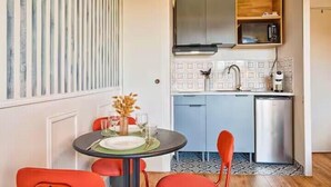 A compact kitchen with a microwave, sink, and cabinets, a dining table with chairs, and a decorative vase. - Studio with balcony in Villers-sur-Mer (Villers-sur-Mer)
