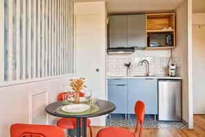 A compact kitchen with a microwave, sink, and cabinets, a dining table with chairs, and a decorative vase. - Studio with balcony in Villers-sur-Mer (Villers-sur-Mer)