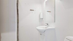 Un baño con lavamanos blanco, espejo y cortina de ducha.