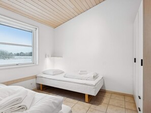 A bedroom with a bed, a window, a bedside table, and a wardrobe. - 4 Star Holiday Home in Pandrup (Pandrup)