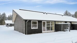 Un edificio moderno con techo nevado, ventanas grandes y puerta de garaje.