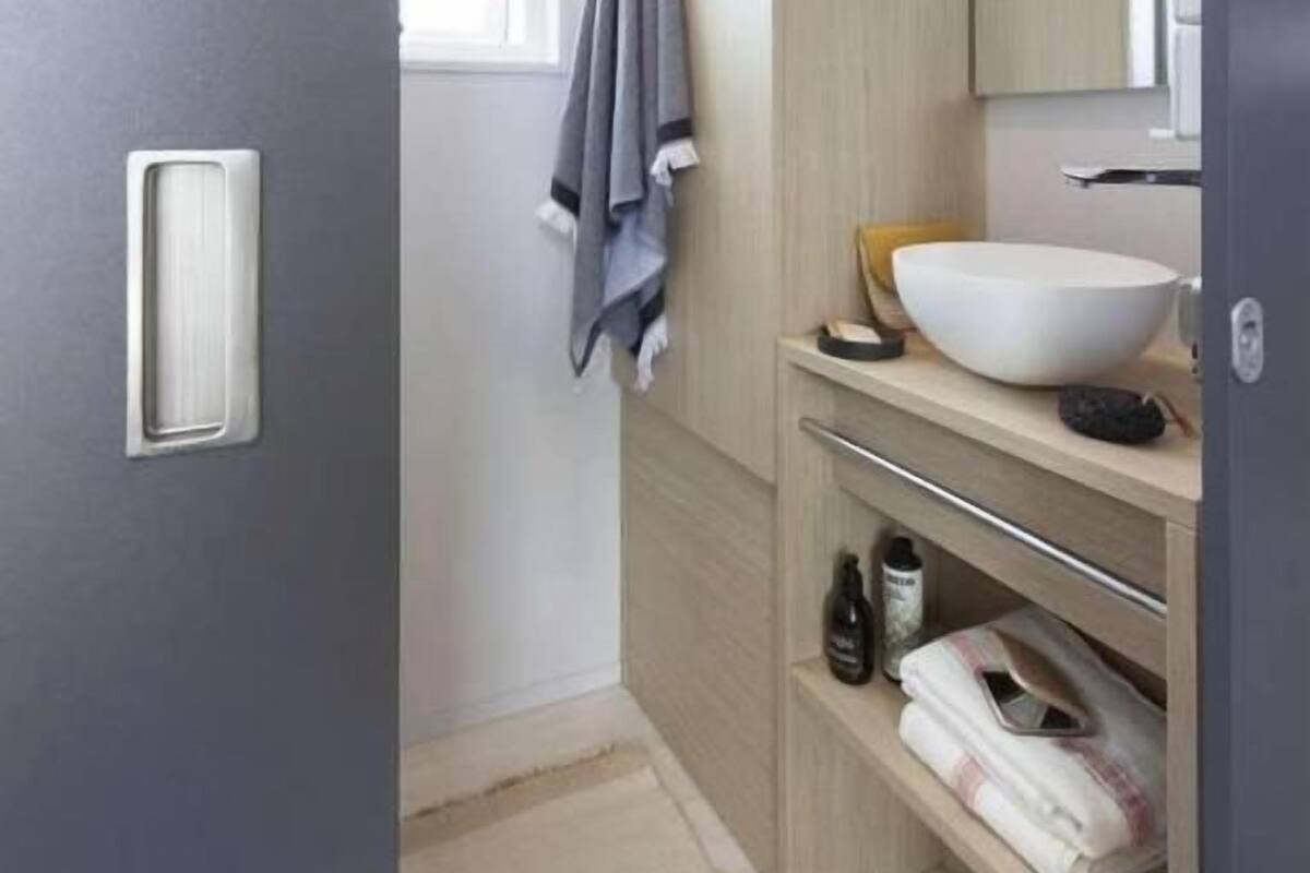 A bathroom with a white sink, wooden vanity, and a towel hanging on the wall.