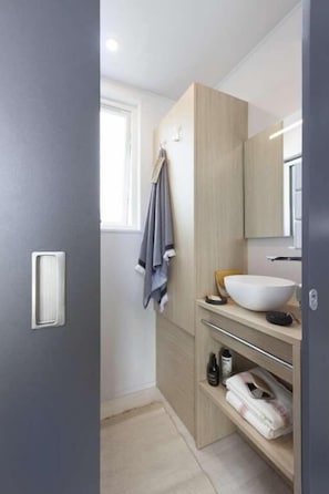 A bathroom with a white sink, wooden vanity, and a towel hanging on the wall.