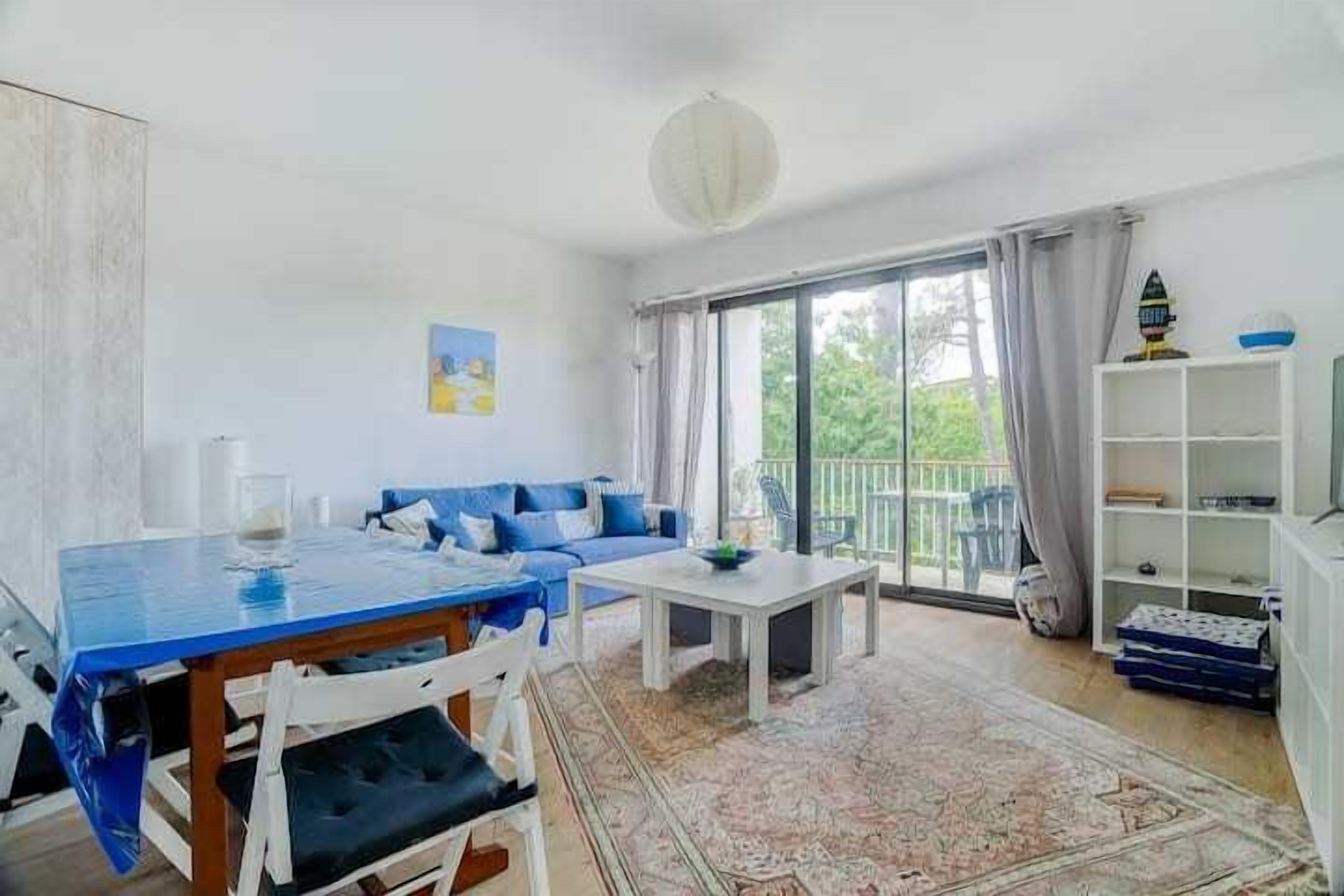 Una sala de estar moderna con una mesa de comedor, sofá y un ventanal con cortinas.