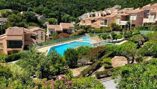 Ett bostadsområde med en swimmingpool omgiven av grönska och hus i medelhavsstil.