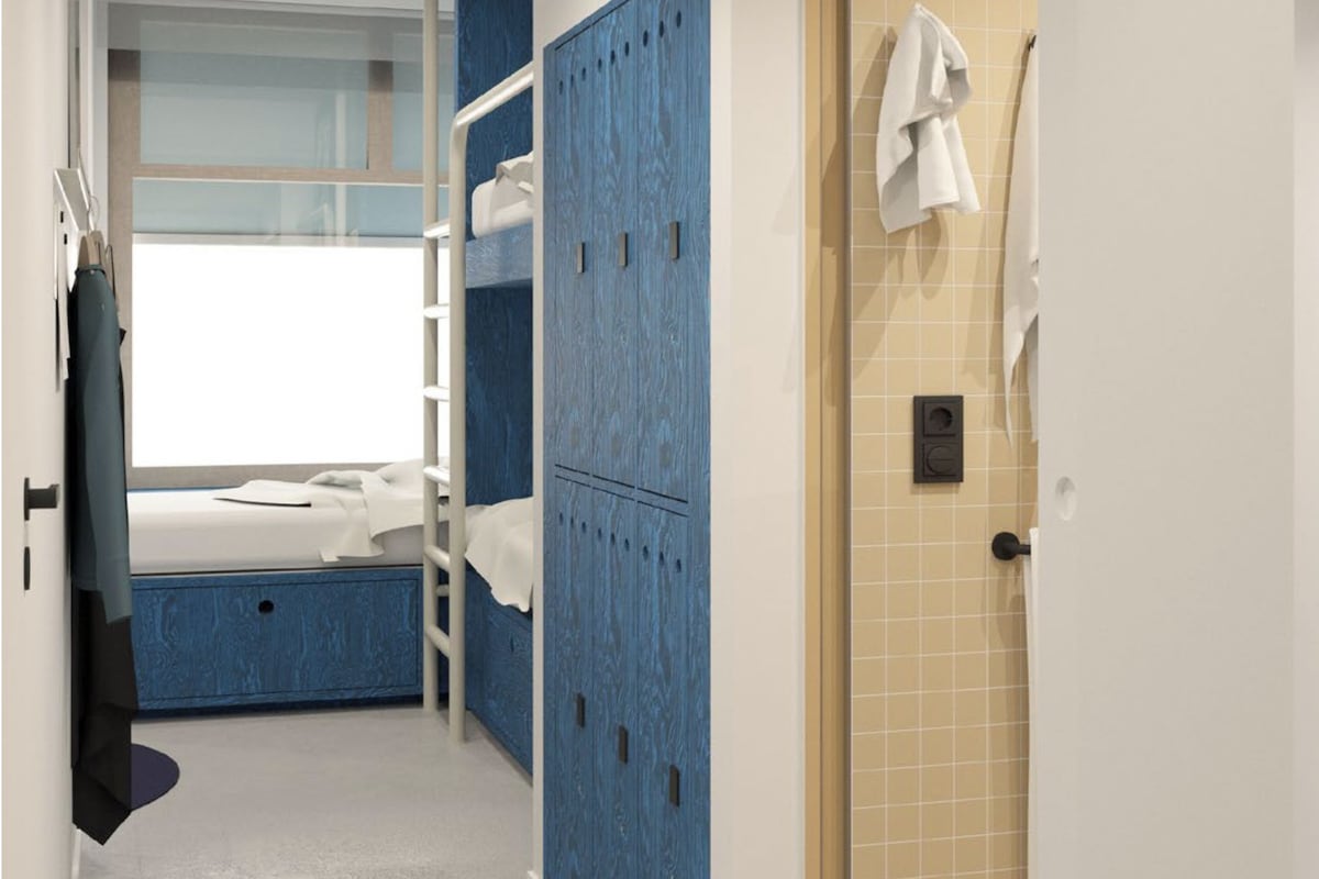A hotel room with a bunk bed, a wardrobe, and a shower area.