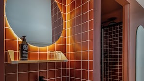 Un baño con un lavamanos grande y rectangular, un espejo redondo y una zona de ducha.