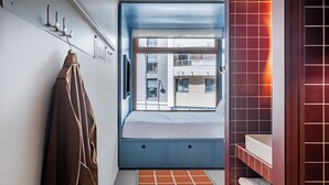 Un dormitorio con cama, ventana, baño con lavamanos y perchero.