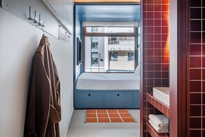 A bedroom with a bed, a window, a bathroom with a sink, and a coat rack. - Hôtel Super (Paris)
