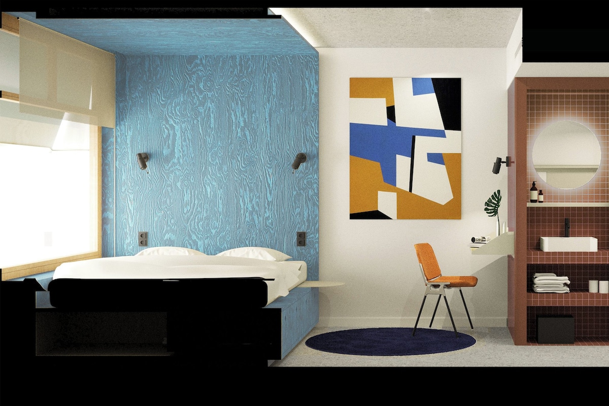 A modern bathroom with a blue wall, a sink, a toilet, and a large mirror.