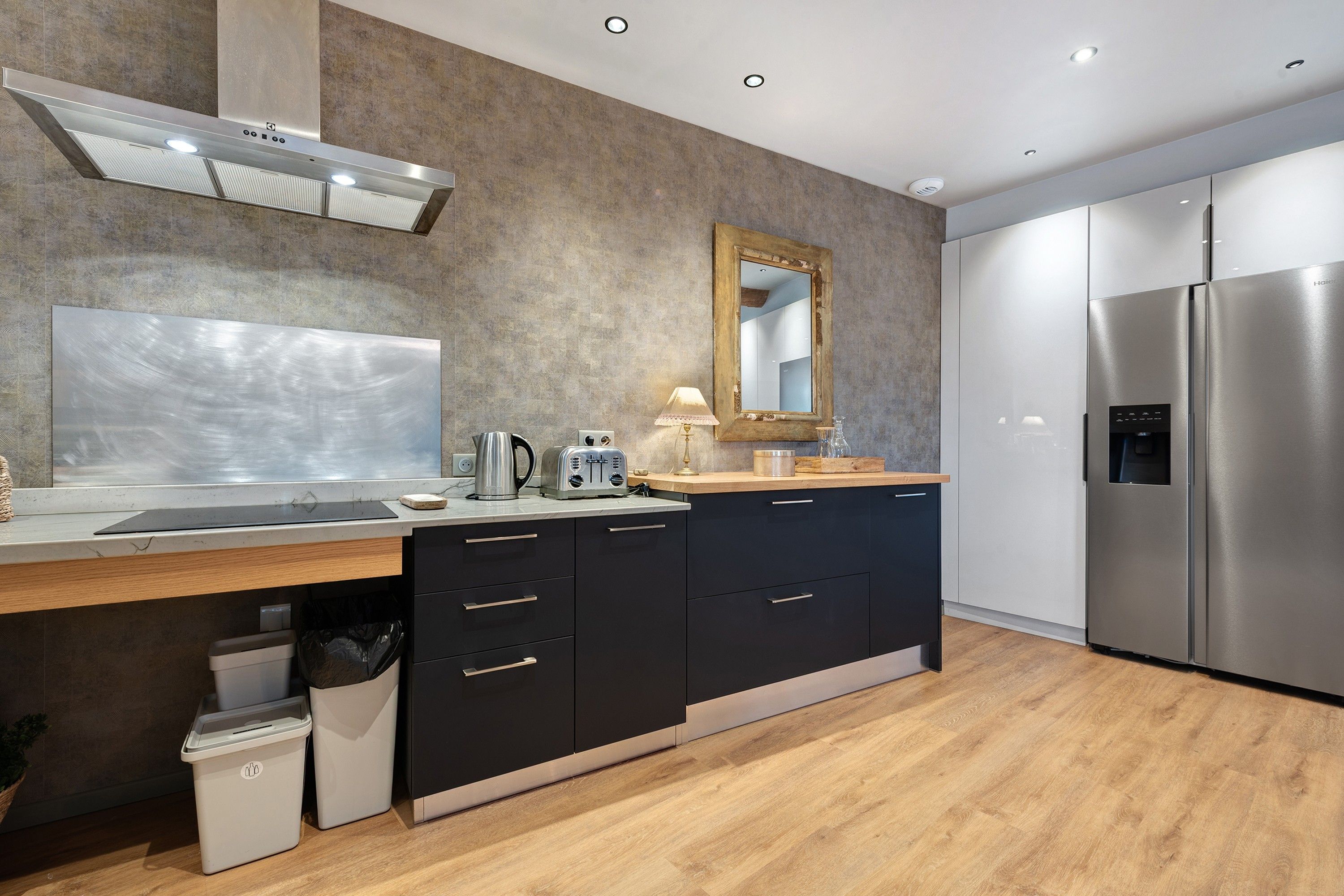 A modern kitchen with a stainless steel refrigerator, a built-in oven, and a wooden countertop.