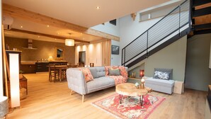 A spacious living area with a sofa, a round coffee table, and a staircase. - Holiday Home “L’Escale Pibeste” with Mountain View, Wi-Fi and Air Conditioning (Agos-Vidalos)