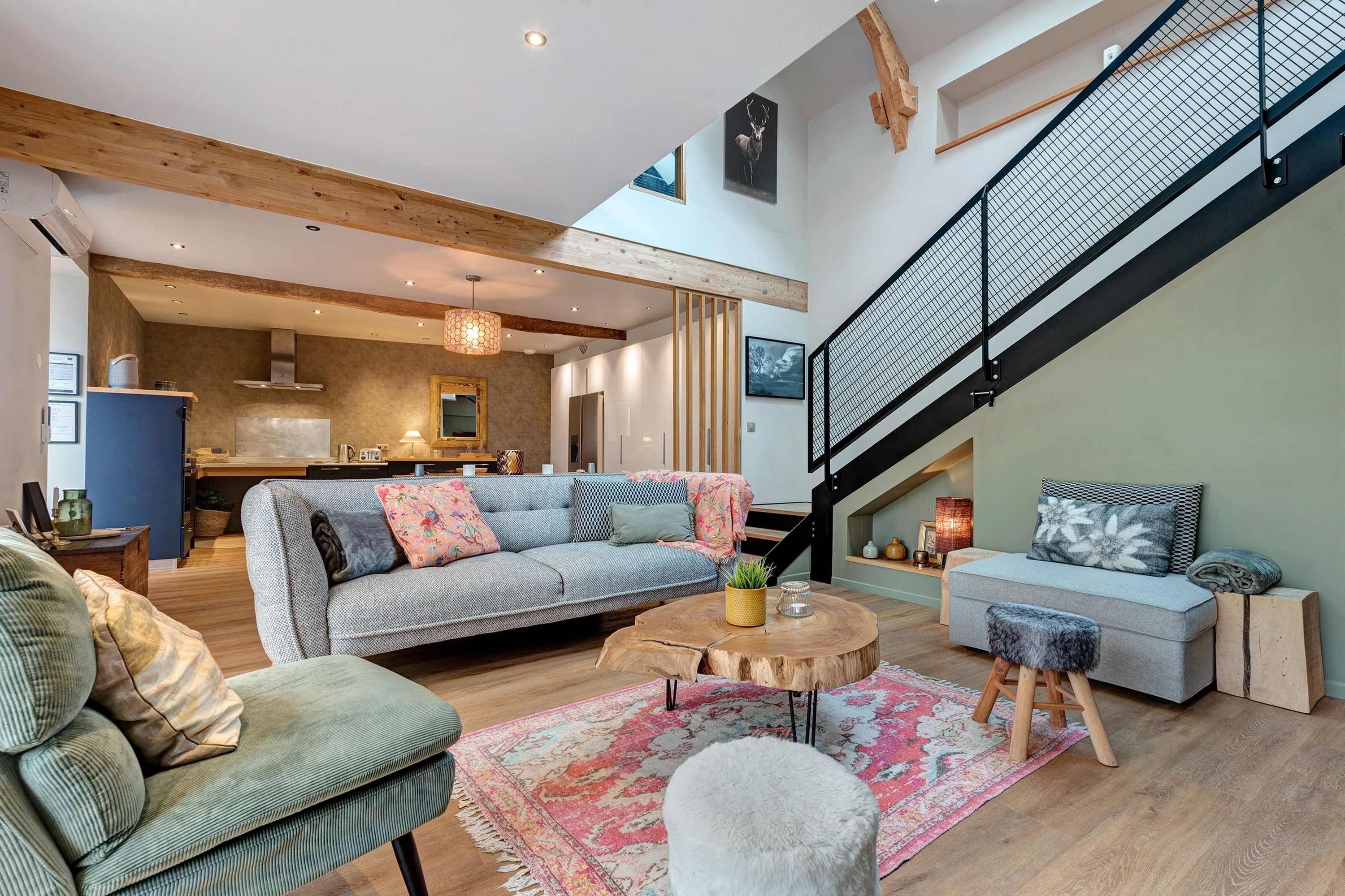 Un intérieur moderne comprenant un escalier, un ensemble de canapés, un coin repas et une cuisine.