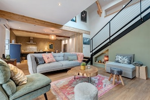 A modern interior with a staircase, a sofa set, a dining area, and a kitchen.