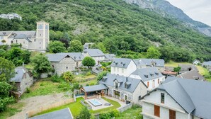 A village with stone buildings, a church tower, and a pool area. - Holiday Home “L’Escale Pibeste” with Mountain View, Wi-Fi and Air Conditioning (Agos-Vidalos)