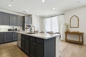 Une cuisine moderne avec des meubles de couleur sombre, un îlot central et une console en bois.