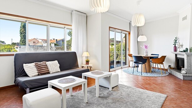 A modern living room with a sofa, a dining table, and a fireplace. - GuestReady - Charming retreat with balcony in Gaia (Vila Nova de Gaia)