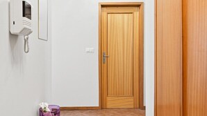 A hallway with a wooden door, a bench, a telephone, and a trash bin. - GuestReady - Charming retreat with balcony in Gaia (Vila Nova de Gaia)