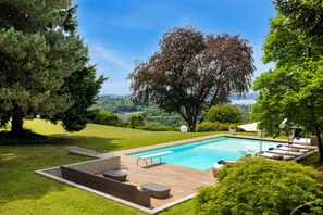 Une piscine avec une terrasse en bois, des chaises longues et une vue sur le paysage.
