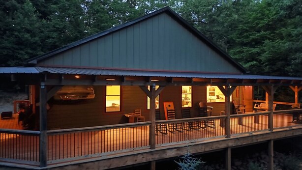Une cabane dotée d’un porche couvert, d’une terrasse et d’une grande fenêtre.