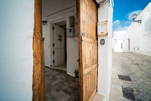 Eine enge Kopfsteinpflasterstraße mit weißen Gebäuden, Holztüren und einem gefliesten Boden.