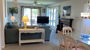A living room with a sofa, a glass-top dining table, chairs, a television, a ceiling fan, and a fireplace. - WATERFRONT HOME  Ocean Pines Dog Friendly (Ocean Pines)